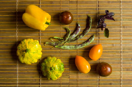 Still life - small spotted squash, asparagus beans, purple Basil, paprika, yellow and chocolate tomatoes on bamboo Matの写真素材