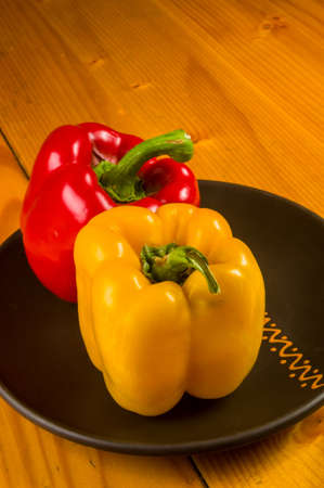a colorful mix of the freshest red and yellow paprika, bell pepper in ceramic plate on wooden background, close upの写真素材