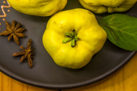 still life - large yellow quince fruits on a ceramic plate, with anise, cinnamon, and walnutsの写真素材