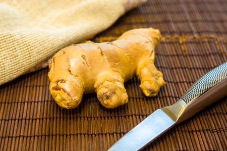 fresh ginger root on bamboo mat with knife and napkin, closeupの写真素材