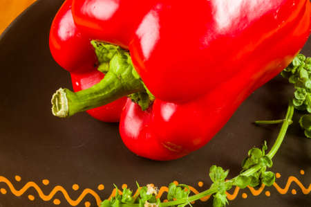 a freshest red paprika, bell pepper in ceramic plate with basil flowers on wooden background, close upの写真素材