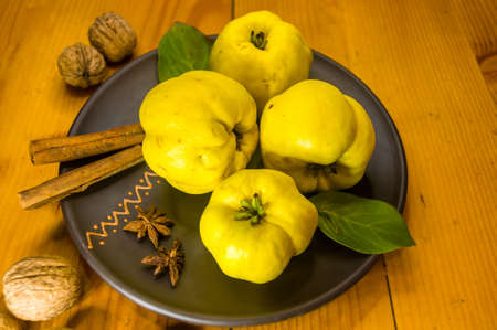 still life - large yellow quince fruits on a ceramic plate, with anise, cinnamon, and walnutsの写真素材