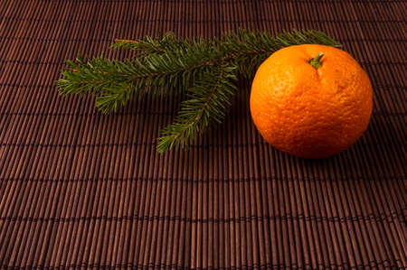 New Year Concept. Christmas decorations from fir-tree branches and the fruits of mandarin orange on bamboo mat backgroundの写真素材