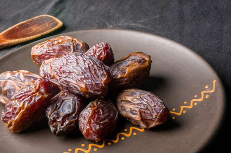 Big luxury dried date fruit in bowls on the dark surface, kurma ramadan kareem concept.の写真素材