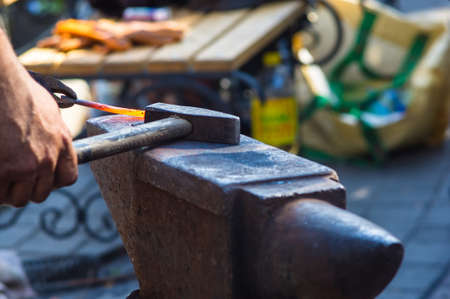 blacksmith performs the forging of hot glowing metal on the anvil, close-upの写真素材
