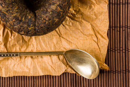 Chinese pressed PU-erh tea on wrapping paper and tea accessories on a bamboo Mat, close-upの写真素材