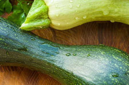 Still life - fresh whole zucchini, eggplant and parsley on a wooden boardの写真素材