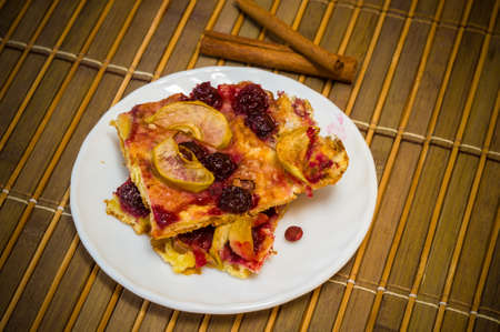 Homemade cookies with fruit in a white saucer on a bamboo mat, close upの写真素材