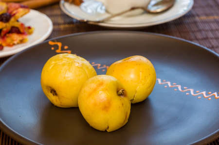 Baked apples with cinnamon in a ceramic bowl on a bamboo mat, close upの写真素材