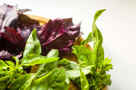 fresh green and purple basil leaves for healthy cooking, herbs and spices on wooden cutting board, closeupの写真素材