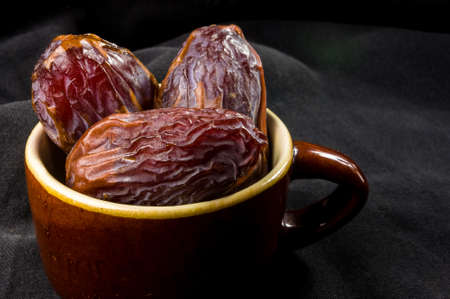 Big luxury dried date fruit in bowls on the dark surface, kurma ramadan kareem concept.の写真素材