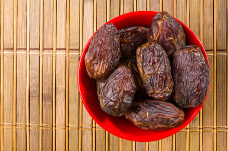 Big luxury dried date fruit in bowls on the bamboo mat, kurma ramadan kareem concept.の写真素材