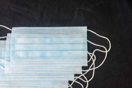 Background concept for news about the novel coronavirus COVID-19 pandemic, antiviral medical mask for protection against coronavirus. Surgical protective mask. Medical respiratory bandage face and thermometer, lettering on copy space.の写真素材