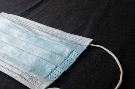 Background concept for news about the novel coronavirus COVID-19 pandemic, antiviral medical mask for protection against coronavirus. Surgical protective mask. Medical respiratory bandage face and thermometer, lettering on copy space.の写真素材