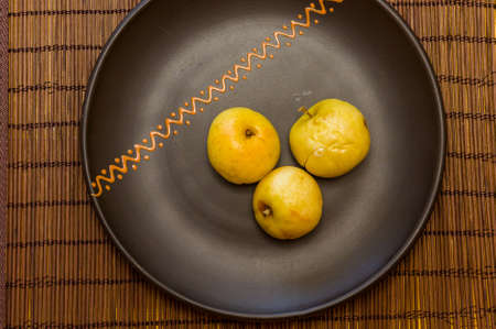 Baked apples with cinnamon in a ceramic bowl on a bamboo mat, close upの写真素材