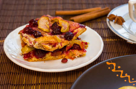 Homemade cookies with fruit in a white saucer on a bamboo mat, close upの写真素材