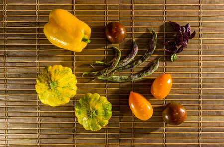 Still life - small spotted squash, asparagus beans, purple Basil, paprika, yellow and chocolate tomatoes on bamboo Matの写真素材