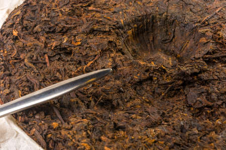 Chinese pressed PU-erh tea on wrapping paper and tea knife, close-upの写真素材