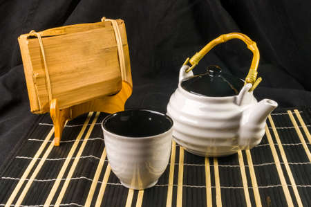Chinese pressed PU-erh tea in bamboo leaf packaging and tea accessories on a bamboo Mat, close-upの写真素材