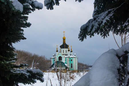 Winter landscape - Orthodox church in the snow among fir-trees on a frosty day