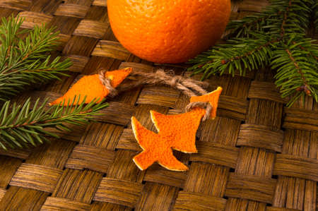 New Year Concept. Christmas decorations from tangerine peel, fir-tree branches and the fruits of mandarin orange on woven mat backgroundの写真素材