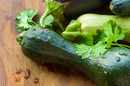 Still life - fresh whole zucchini, eggplant and parsley on a wooden boardの写真素材