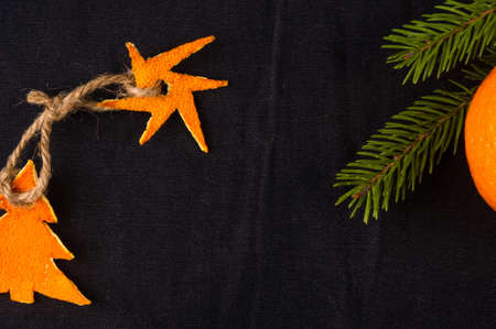 New Year Concept. Christmas decorations from tangerine peel, fir-tree branches and the fruits of mandarin orange on black backgroundの写真素材