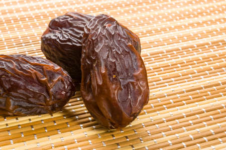 Big luxury dried date fruit on the bamboo mat, kurma ramadan kareem concept.