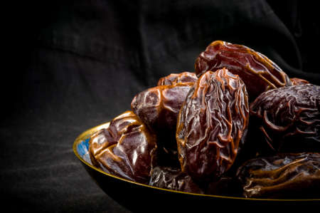 Big luxury dried date fruit in bowls on the dark surface, kurma ramadan kareem concept.の写真素材