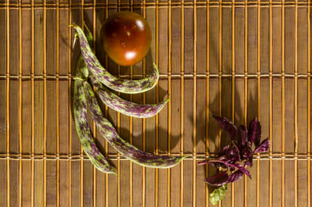 Still life - asparagus beans, purple Basil, yellow and chocolate tomatoes on bamboo Matの写真素材