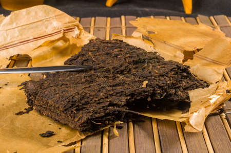 Chinese pressed PU-erh tea on wrapping paper and tea knife, close-upの写真素材