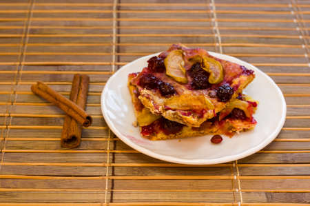 Homemade cookies with fruit in a white saucer on a bamboo mat, close upの写真素材