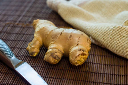 fresh ginger root on bamboo mat with knife and napkin, closeupの写真素材