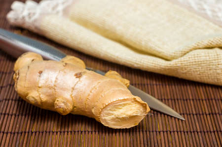 fresh ginger root on bamboo mat with knife and napkin, closeupの写真素材