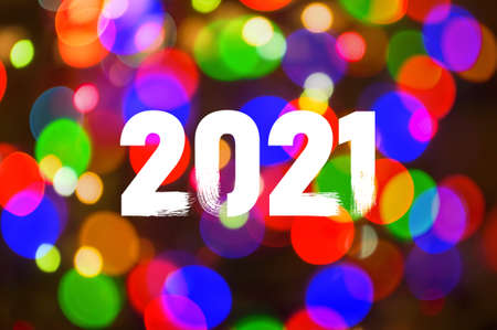 Christmas background-garlands with colorful lights on a decorated Christmas tree, bokeh, Happy New Year 2021 colored symbol and text in trendy flatten style design.の写真素材