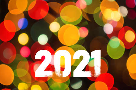 Christmas background-garlands with colorful lights on a decorated Christmas tree, bokeh, Happy New Year 2021 colored symbol and text in trendy flatten style design.の写真素材