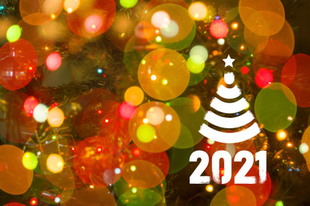 Christmas background-garlands with colorful lights on a decorated Christmas tree, bokeh, Happy New Year 2021 colored symbol and text in trendy flatten style design for seasonal holidays flyers, greetings and invitations cards and christmas themed congratulations and bannersの写真素材