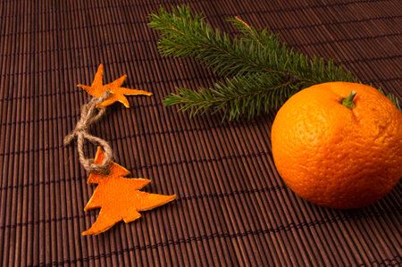 New Year Concept. Christmas decorations hand made from tangerine peel, fir-tree branches and the fruits of mandarin orange on bamboo mat backgroundの写真素材