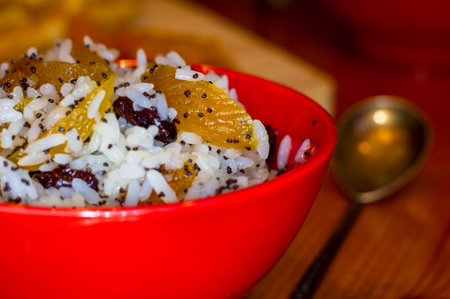 handmade preparation of treats for traditional Orthodox Christmas - rice pudding with fruits, cranberries, honey, nuts, Church candles on a wooden tableの写真素材