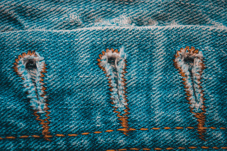 clothing items blue washed faded jeans cotton fabric texture with seams, clasps, buttons and rivets, macroの写真素材
