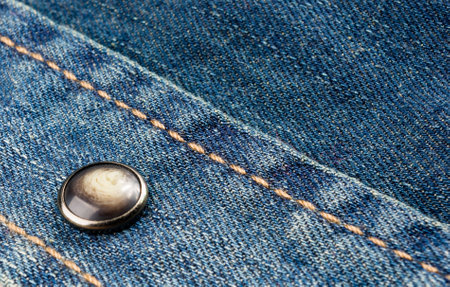clothing items blue washed faded jeans cotton fabric texture with seams, clasps, buttons and rivets, macroの写真素材