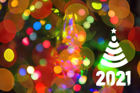 Christmas background-garlands with colorful lights on a decorated Christmas tree, bokeh, Happy New Year 2021 colored symbol and text in trendy flatten style design for seasonal holidays flyers, greetings and invitations cards and christmas themed congratulations and bannersの写真素材