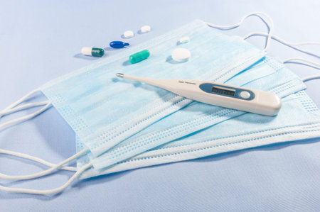 Background concept for news about the novel coronavirus COVID-19 pandemic, antiviral medical mask for protection against coronavirus. Surgical protective mask. Medical respiratory bandage face and thermometer, lettering on copy space.の写真素材