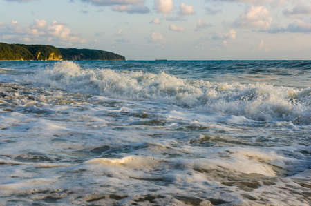 sea landscape is a pebbly beach with waves in white foamの写真素材