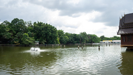 large pond picture There is one working wastewater treatment turbine. On the right is a Thai style pavilion. On the left is a garden. There are shady trees.の写真素材