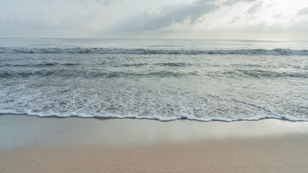 Picture of foamy waves crashing onto the shore of a clean white sand beach. There is no garbage or...