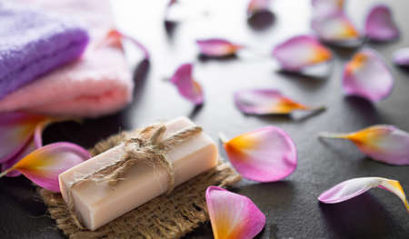 Spa soap with lobe plumeria flowers and towel on black wooden background. aromatherapy massage for...