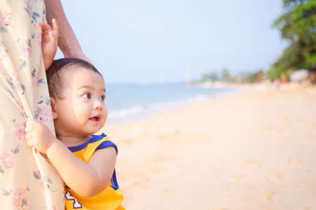 Littel boy 1 year old hugging mom with excitement and joy on blue sea blur image. mom and child in travel summer holiday concept.の写真素材