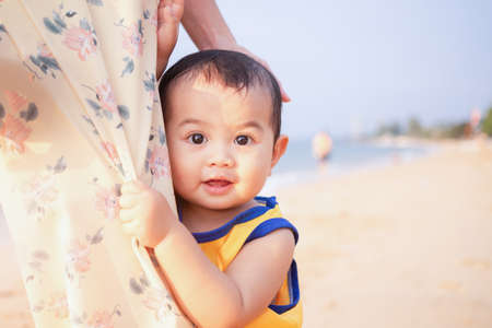 Littel boy 1 year old hugging mom with excitement and joy on blue sea blur image. mom and child in travel summer holiday concept.の写真素材
