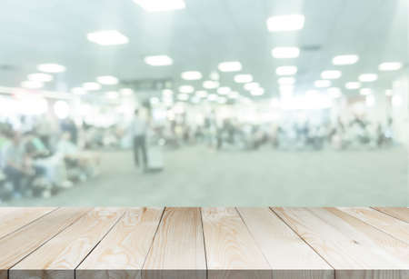 blured airport with wooden perspective table for add text or products in the presentation. abstract people passengers at station aerodrome interiors. transportation or business concept.の写真素材